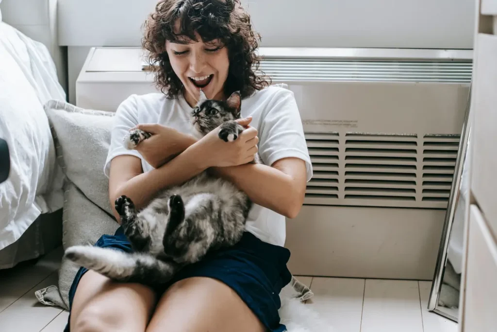 Smiling cat owner sharing a playful greeting with a relaxed tabby