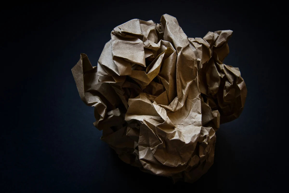 A loosely crumpled ball of brown paper against a dark background.