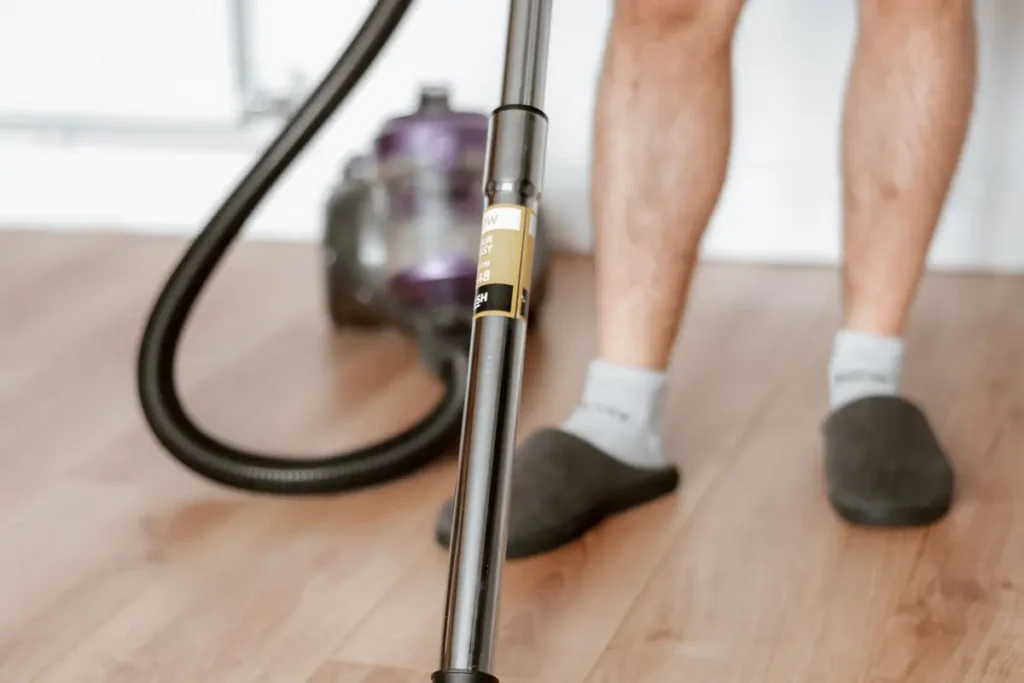 Person vacuuming a light wooden floor indoors